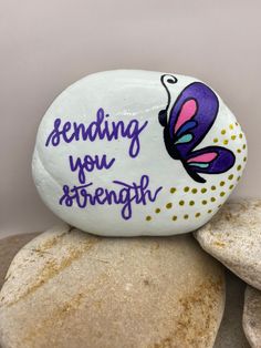 a painted rock with the words sending you strength on it sitting on top of some rocks