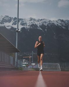 a woman running on a tennis court with mountains in the background