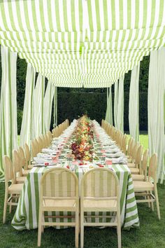 a long table is set with green and white striped cloths for an outdoor party