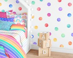 a child's bedroom decorated with colorful polka dot wallpaper and rainbow bedding