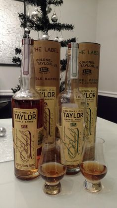 three bottles of taylor's single cask whiskey sitting on a table next to two glasses