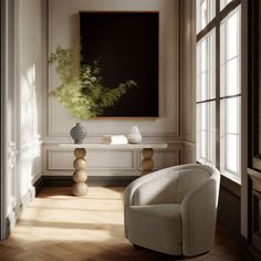 a living room with a chair, table and large painting in it's center