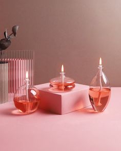 two pink vases filled with liquid next to each other on top of a table