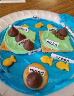 a blue plate topped with cake covered in green frosting and animals on top of it