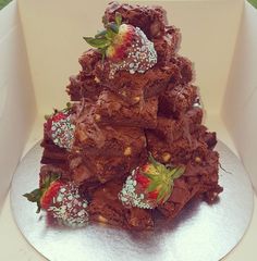 a pile of brownies with strawberries on top in a white cardboard box,