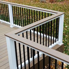 a wooden deck with black railings and white hand rails