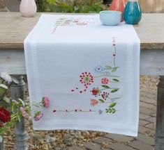 a table with some vases on it and a white table cloth that has flowers painted on it