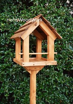 a wooden bird house in front of some bushes