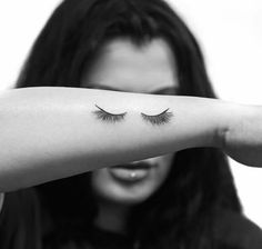 a woman is holding her arm with eyelashes on it