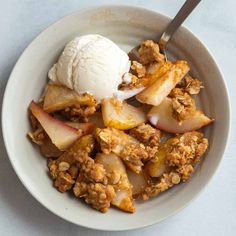 a bowl filled with fruit and ice cream on top of a white countertop next to a spoon