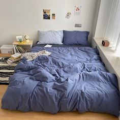 a bed with blue sheets and pillows in a bedroom next to a white window sill