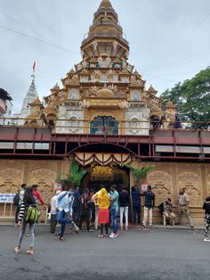 many people are standing in front of a large building that is decorated with gold and white designs