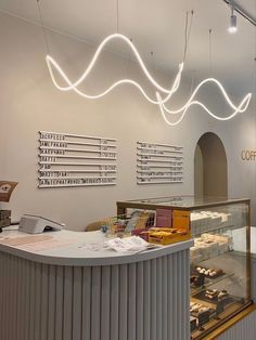 the interior of a coffee shop with lights hanging from the ceiling and various types of pastries on display