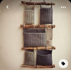 a wall hanging made out of knitted material and wooden pegs with two bags on it