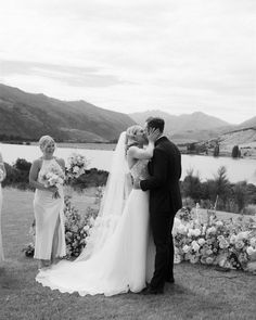 a bride and groom kiss in front of their wedding party on the lawn at this outdoor ceremony