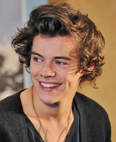 a young man with curly hair smiling at the camera