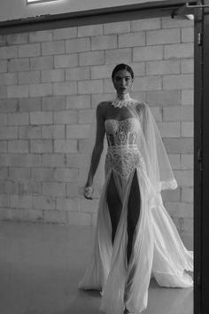 a model walks down the runway in a white gown with sheer sleeves and high slits