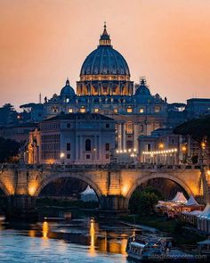 the dome of st peter's cathedral is lit up at night over the river