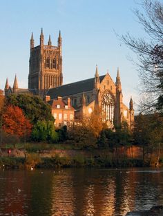 a large cathedral sitting on top of a lush green hillside next to a body of water