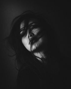 a black and white photo of a woman's face with her hair blowing in the wind