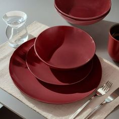 red plates and silverware sit on a linen placemat