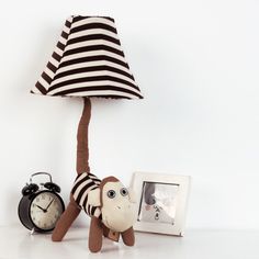 a stuffed monkey under a lamp next to an alarm clock