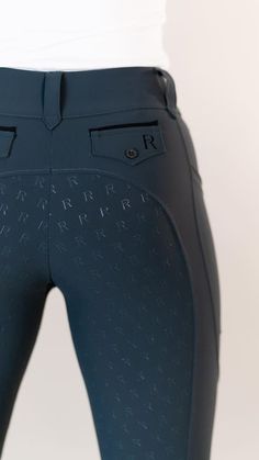 the back view of a woman's equestrian riding pants with black lettering on it