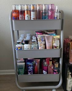 a cart filled with lots of different types of cosmetics and personal care products next to a wall