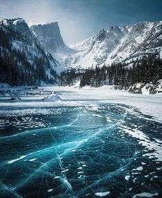 an icy lake surrounded by snow covered mountains