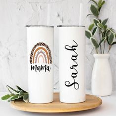 two personalized tumblers sitting on top of a wooden tray next to a potted plant