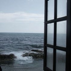 an open window looking out at the ocean and crashing waves in the water from outside