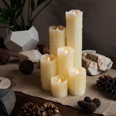 a group of candles sitting on top of a table next to pine cones and rocks