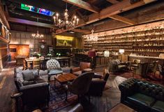 an old fashioned bar with leather chairs and chandeliers