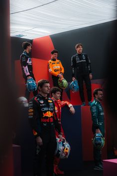 three men in racing gear standing next to each other with helmets and gloves on their hands