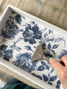 a person using a trowel to cut fabric with scissors in a box on a table