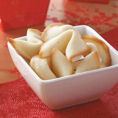 a white bowl filled with cut up food on top of a red tablecloth covered table