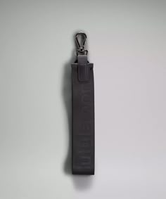 a black keychain hanging from the side of a white wall