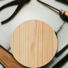 a circular wooden object sitting on top of a table next to pliers and scissors