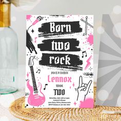 a pink and black card with the words born two rock on it next to a bottle