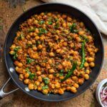 a pan filled with chickpeas on top of a table next to other dishes