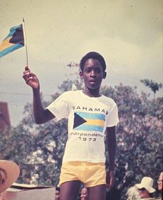 a young boy holding a flag and wearing yellow shorts