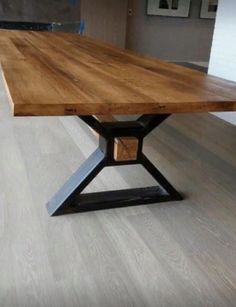 a wooden table sitting on top of a hard wood floor next to a white wall