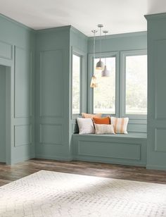 a living room with blue walls and wooden floors, two windows, and a white rug on the floor