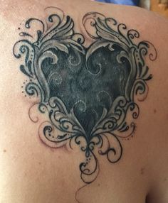 a heart tattoo on the back of a woman's shoulder