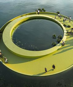 people are standing on the edge of a large circular structure that is floating in water