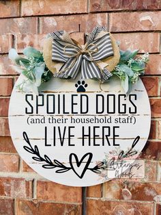 a wooden sign that says spoiled dogs and their household staff live here with a bow on it