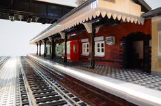 there is a model train station with tracks and a red door on the building next to it