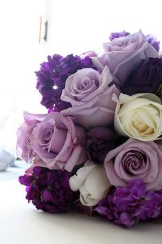 a bouquet of purple and white flowers sitting on top of a table