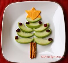 a white plate topped with apples and crackers next to an apple shaped christmas tree