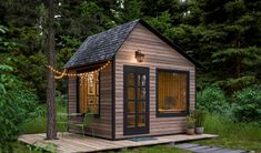 a small wooden cabin in the woods with lights on it's windows and door